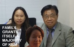 KNM Director Diverts 155M ESOS Shares to Family A woman in a business suit reviews documents at a desk, with a company logo visible in the background.