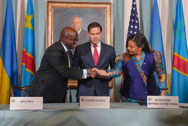 2025 DRC–Rwanda peace agreement Foreign ministers of DRC and Rwanda shake hands while signing peace documents as US Secretary of State looks on in Washington ceremony.