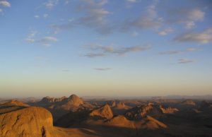 Algeria Bus Collision Kills 34 in Tamanrasset A damaged bus rests on a dusty road in Tamanrasset Province, with emergency responders and debris scattered nearby after a fatal collision.