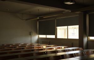 ChatGPT Upends US Classrooms Since Late 2022 Teacher reviewing student essays while a phone displays ChatGPT on the desk in a dimly lit classroom.