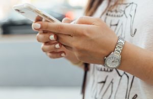 China Quarantine Drives Mobile Game Downloads 80% A person in quarantine holds a smartphone displaying a mobile game, with a window showing a locked-down city street.