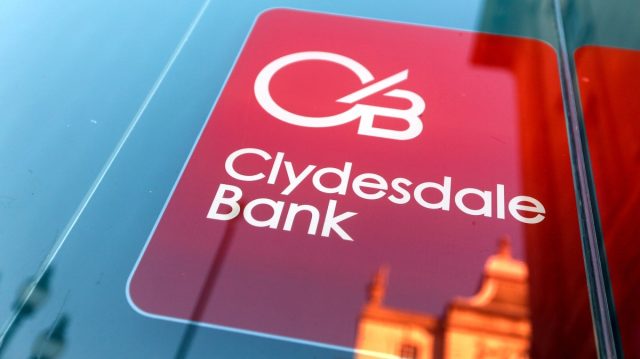 Clydesdale Bank Yorkshire Bank Payment Delay Customers checking empty bank accounts on smartphones outside a Clydesdale Bank branch in Yorkshire