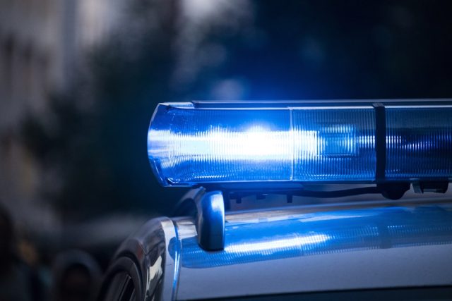 Police Probe KNM Group Proxy Voting Irregularities After Document Seizure Police officers carrying boxes of documents out of a corporate office building during a commercial crime investigation.