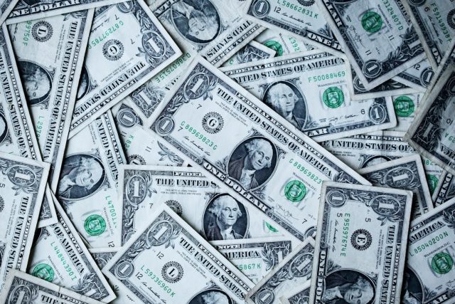 Laos Default Risk Rises as Debt Exceeds 70 Percent of GDP Laotian kip banknotes and coins arranged on a table with a financial newspaper showing currency exchange rates in the background.