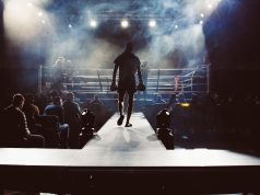 Lauren Price Unifies Welterweight with Five Titles Lauren Price in a boxing ring wearing championship belts after unifying the welterweight division.