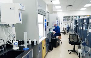 Kyntra Bio Bets All on Single Experimental Cancer Drug A scientist in a lab coat examines a vial labeled with an experimental cancer drug in a modern laboratory setting.