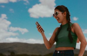 Grok Chatbot Hits App Stores with Deep AI Understanding A smartphone screen displays the Grok chatbot interface, with a Tesla Optimus robot visible in the background.