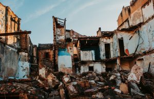 Afghanistan Herat 6.3 Aftershock Kills 1, Injures 65 Collapsed mud-brick homes in a Herat village with rescue teams searching debris under a dust-filled sky after the 6.3 aftershock.