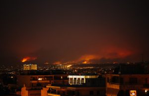 Portugal Arrests 12 Arson Suspects After Deadly Wildfires Portuguese police officers escort a handcuffed suspect near a charred forest landscape in Northern Portugal.