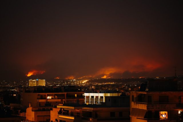 Portugal Arrests Twelve Suspected Arsonists After Deadly Wildfires Portuguese police officers escort a handcuffed suspect near a charred forest landscape in Northern Portugal.