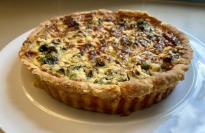 King Charles Coronation Quiche Debuts May 2023 A coronation quiche with spinach, broad beans, and tarragon on a serving platter at a royal celebration.