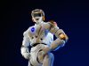 Honor Robot Beats Human Half Marathon Record A humanoid robot running on a Beijing race course, crossing a finish line with spectators watching.