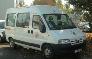 Minibus Collision Kills 18 Shia Pilgrims in Iraq Two damaged minibuses on a dusty Iraqi road after a collision, with emergency responders and debris scattered nearby.