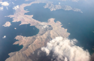 Pentagon Releases 2024 Gulf of Oman UAP Mission Report Redacted Pentagon mission report page titled DOW-UAP-D27 overlays a dark aerial view of the Gulf of Oman at dusk.