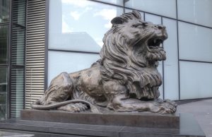 HSBC Bank in shaky relationship with Chinese Government Bronze lion statue outside HSBC global headquarters at Canary Wharf, London