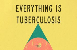 John Green Releases TB History Book Everything Is Tuberculosis Author John Green holds a copy of his new book surrounded by vintage TB hospital artifacts in a softly lit archive room.