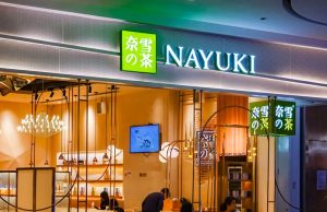 Nayuki Raises US$656M in Hong Kong IPO A barista prepares bubble tea drinks at a Nayuki shop, with cups of colorful tea on the counter.