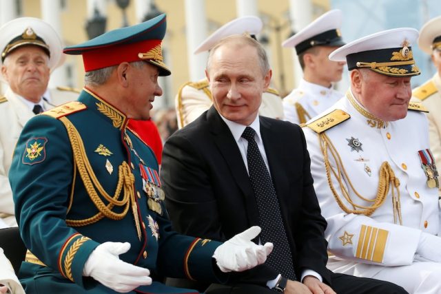 Sergei Shoigu Corruption Probe Kremlin Sergei Shoigu in military uniform at a press conference, with Russian flags in the background.