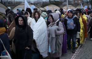 2.8 Million Flee Ukraine as Russian Strikes Hit West Ukrainian refugees carrying bags cross a border checkpoint into eastern Europe, fleeing Russian strikes in western Ukraine.