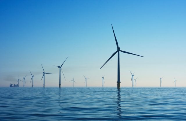 China's Clean Energy Capacity Surpasses Fossil Fuels for First Time Solar panels and wind turbines stretch across a Chinese landscape under a clear blue sky.