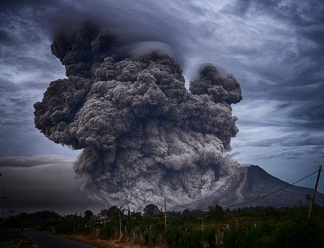 Ethiopia's Hayli Gubbi Volcano Eruption Disrupts Arabian Peninsula Flights Ash plume rising from Hayli Gubbi volcano in Ethiopia's Afar Region, with grounded airplanes visible on a distant tarmac.